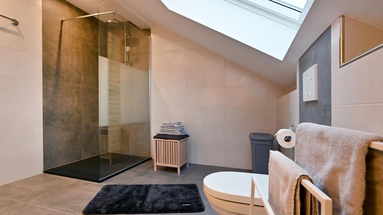 Ein modernes Badezimmer mit einer begehbaren Dusche und viel natürlichem Licht. Die Einrichtung ist minimalistich und stilvoll, mit einem neutralen Farbschema.