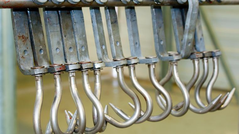 Eine Reihe von Metallhaken hängt an einer Stange. Sie sind zur Befestigung und Aufhängung von Objekten geeignet.