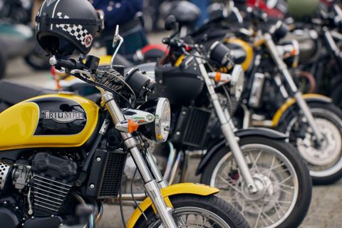 Une série de motos de différentes couleurs est rangée côte à côte. La moto à l'avant est jaune et a un design classique.