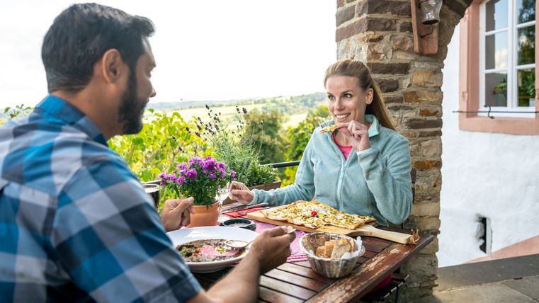 Un couple mange sur une terrasse avec vue sur le paysage.