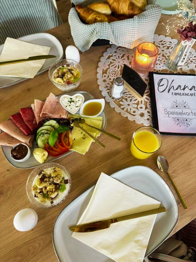 Een aantrekkelijk gedekte tafel met verschillende ontbijtgerechten. Er zijn vleeswaren, kaas, verse groenten en een drankje.