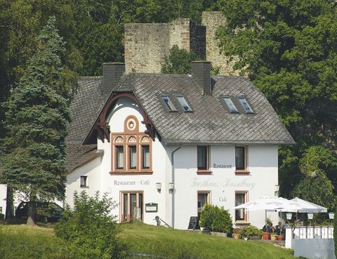 <p>Op de voorgrond ziet men een wit huis met de opschriften "Restaurant Café" en "Forsthaus Kasselburg". Voor staan twee grote parasols en tafels met stoelen. Op de achtergrond is een kasteel en bomen.</p>
