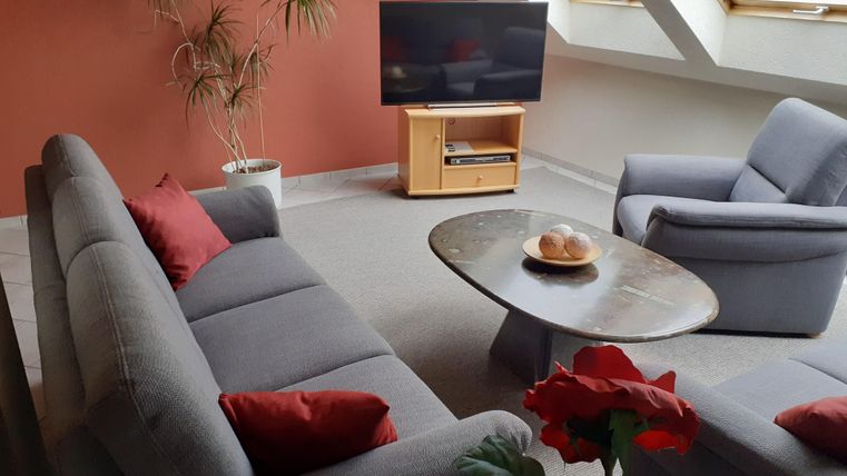 A cozy living space with gray sofas and a round table. Large windows let in plenty of light.