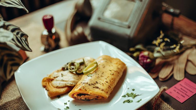 Gevulde, goudbruin gebakken pannenkoeken op een wit bord.