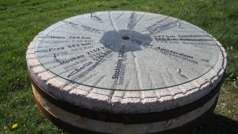 A millstone with distances to various towns on a meadow.
