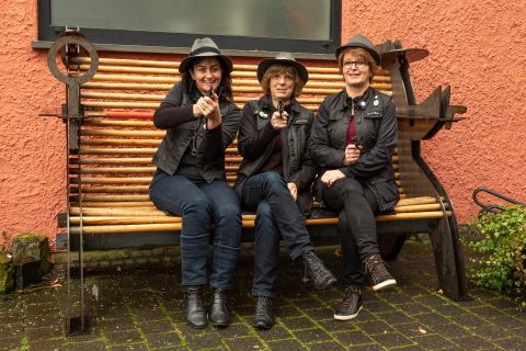 Les trois guides de crime, assises sur le banc de crime devant l'office du tourisme de Hillesheim, visent le photographe avec des pistolets.