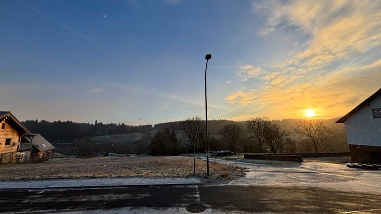 A picturesque sunrise over a rural landscape. In the foreground, you can see a quiet road and winter settings.