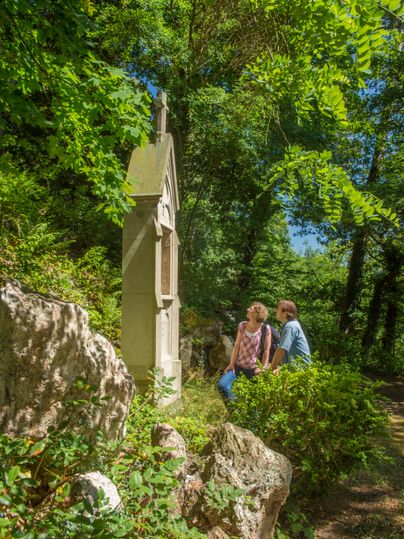 Twee mensen kijken naar een monument in het bos op de kruisweg van Adenau.