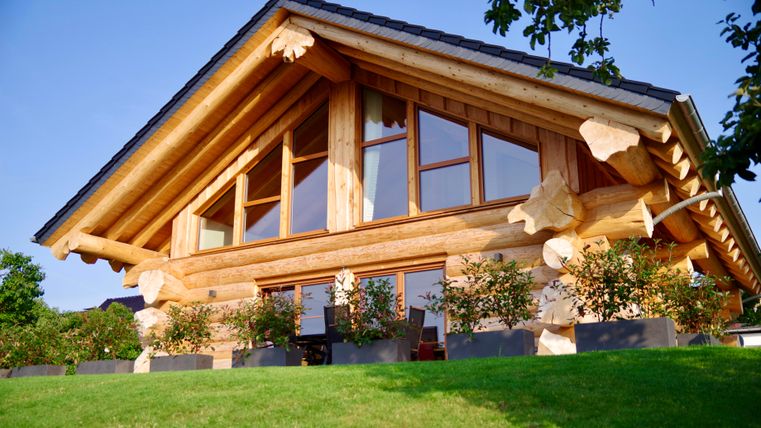 Een modern naturaalkloofhuis met grote ramen in een omheinde tuin. De architectuur verbindt traditionele en hedendaagse elementen.