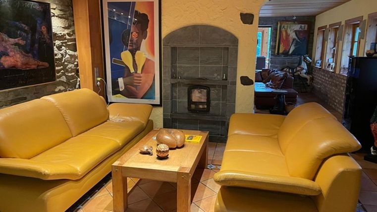 A cozy living room with two yellow sofas and a wooden table. In the background, there is a fireplace and a piece of art on the wall.