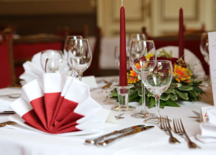 Een elegant gedekte tafel met rood en wit bestek. Decoratieve servetten en bloemenarrangementen creëren een feestelijke sfeer.