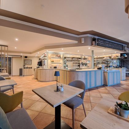 A modern café with a bright interior and an inviting counter. Comfortable chairs and tables create a cozy atmosphere.