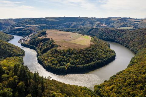 Vue aérienne d'une boucle de rivière dans un paysage boisé avec des champs.