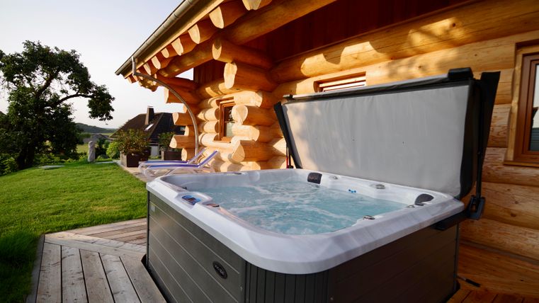 Un jacuzzi sur une terrasse en bois à usage exclusif.