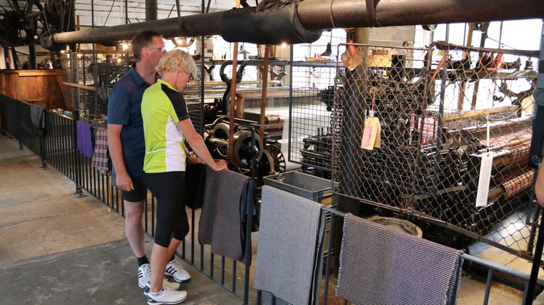 Twee mensen kijken naar machines in een historische textielfabriek.