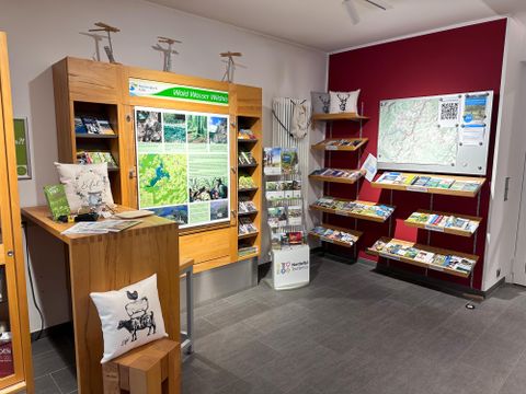 An information center with wooden shelves and brochures. A map hangs on the wall and there are inviting seating options.