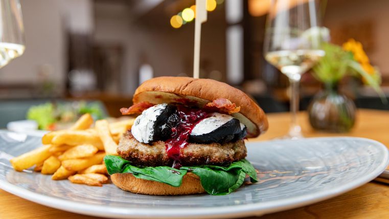 Ein saftiger Burger mit frischem Salat, Speck und einer besonderen Sauce. Dazu gibt es knusprige Pommes frites.