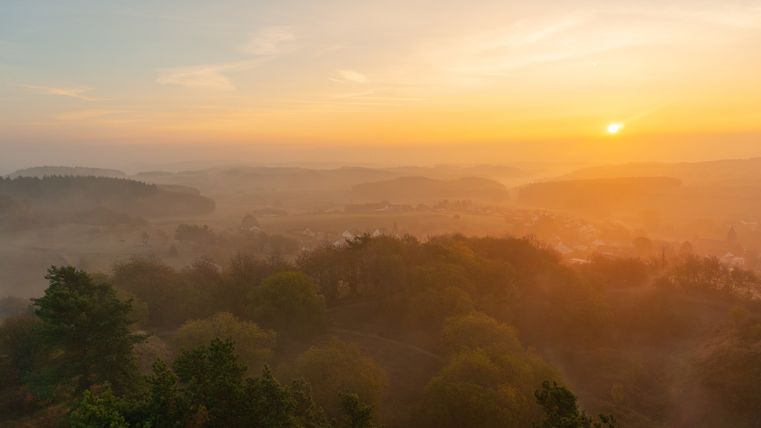 Zonsopgang over mistige heuvels en bebost landschap