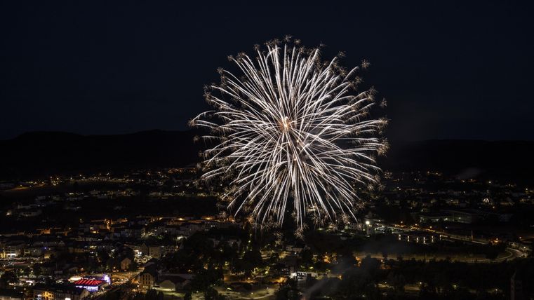 Große Explosion eines Feuerwekskörpers hoch oberhalb der Stadt Gerolstein erhellt die dunkle Nacht.