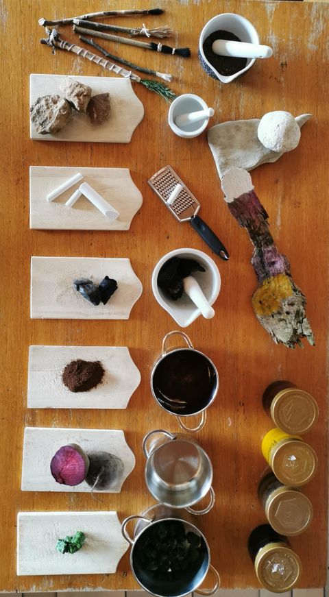 A collection of various ingredients and utensils on a wooden board. The items are neatly arranged, including powders, containers, and tools.
