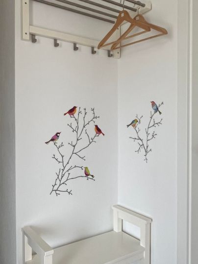 Ein heller Flur mit einer Holzablage und einem Kleiderbügel. An der Wand sind wunderschöne Vogelmotive auf Zweigen zu sehen.
