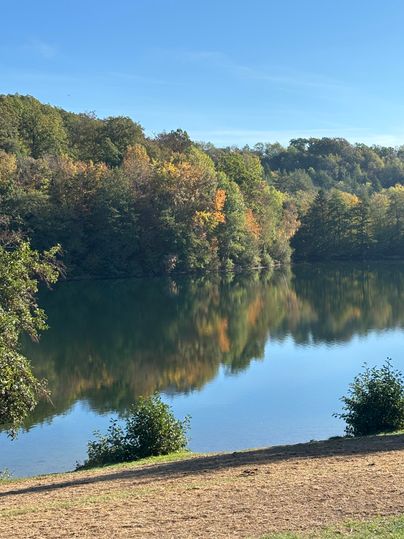 A quiet lake surrounded by colorful foliage. The water reflects the colors of the trees and the blue sky.