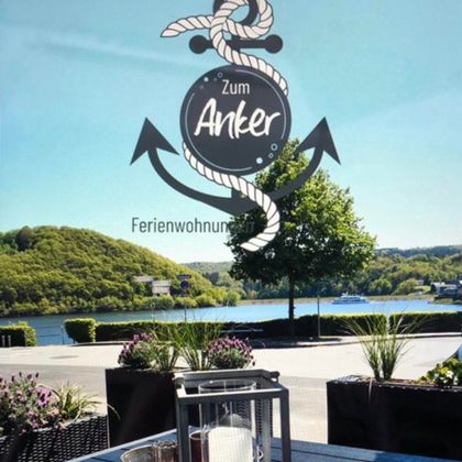 A modern apartment with an open kitchen and a cozy living area. The furniture is in neutral colors, with two small tables in the center.