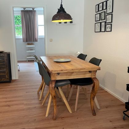 A cozy dining area with an expandable wooden table is located right next to the kitchen.