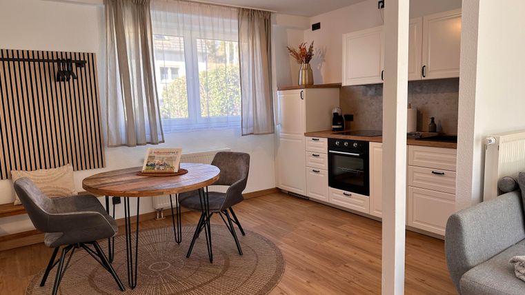 Een gezellige woonruimte met een ronde tafel en vier stoelen. De heldere, moderne keuken is goed uitgerust en biedt veel natuurlijk licht.