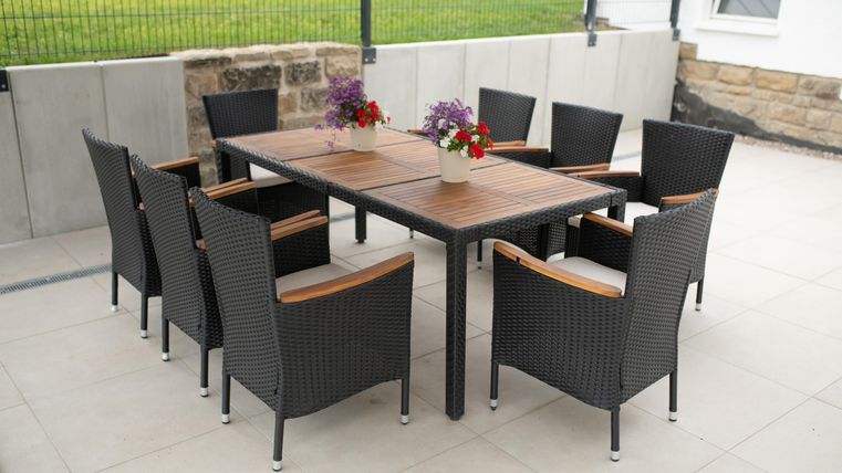 Ein eleganter Esstisch aus Holz mit acht Stühlen auf der Terrasse  für gemütliche Nachmittage oder Grillabende.