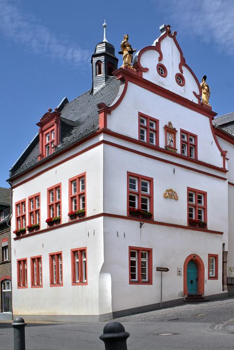 Un bâtiment historique avec une façade blanche et des accents rouges. Il a de nombreuses fenêtres et une structure de toit frappante.
