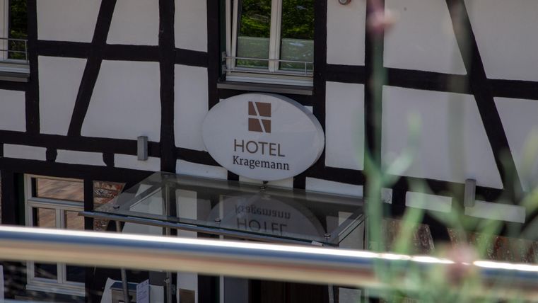 Een hotel in een klassieke vakwerkstijl met een modern bord. De ingang is goed zichtbaar en uitnodigend.