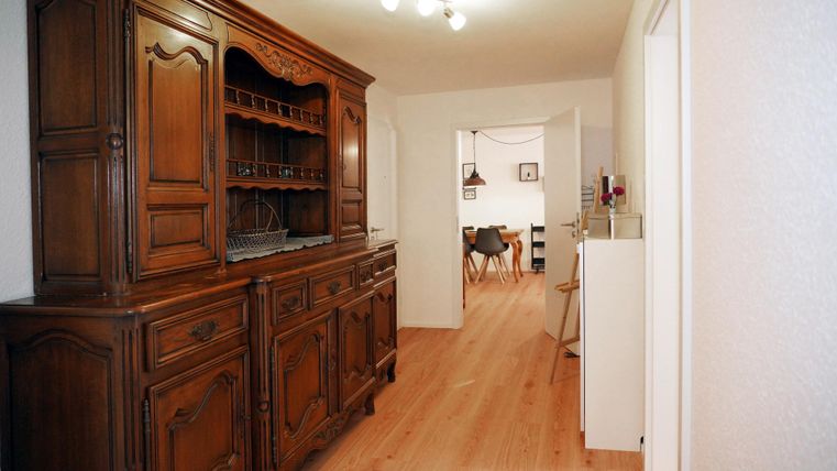 A cozy hallway with a classically designed wooden wardrobe. The long hallway connects the rooms.