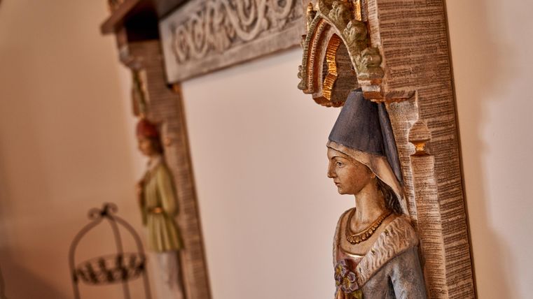 Eine kunstvolle Veranda mit dekorativen Statuen und einem eleganten Rahmen. Die Figuren haben traditionelle Kleidung und verleihen dem Raum einen nostalgischen Charme.
