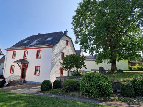 La photo montre l'extérieur de la maison de vacances "Das Gloria". C'est l'ancienne maison paroissiale à Uedelhoven, commune de Blankenheim dans l'Eifel, construite en 1807 et entièrement rénovée par la propriétaire Kirsten Mauer en coordination avec l'autorité de protection des monuments entre 2024 et 2025.