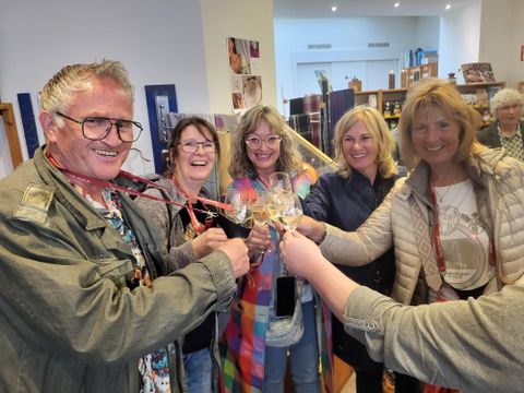 Un groupe de cinq personnes porte un toast avec des verres et fête ensemble. Tous sourient et semblent joyeux dans un environnement accueillant.