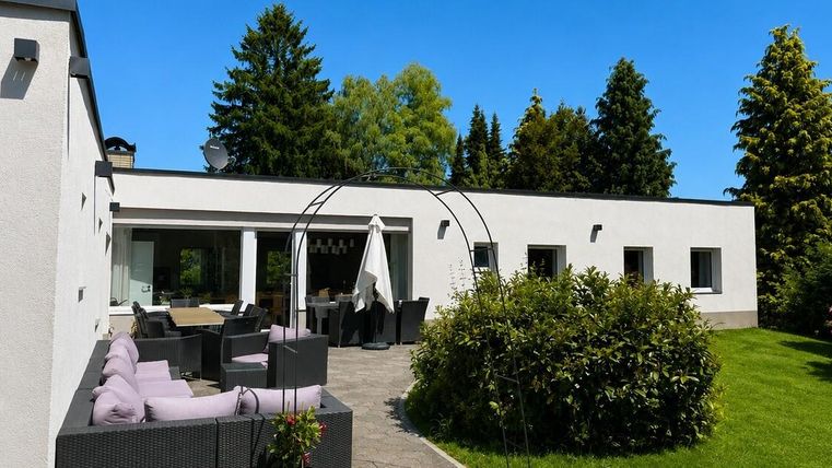 Een modern huis met een mooie buitenruimte. Groene gazons en zithoeken nodigen uit tot ontspannen.