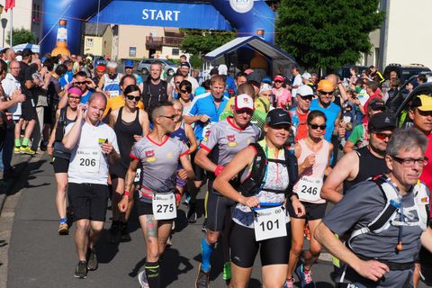 Eine Gruppe von Läufern startet einen Wettkampf. Sie tragen Sportbekleidung und lächeln, während sie die Strecke entlanglaufen.