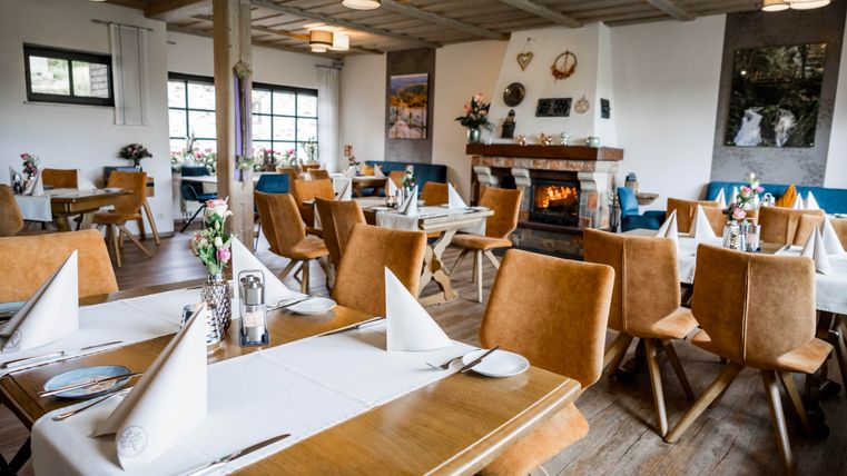 A cozy restaurant with wooden furniture and beautiful table decorations. In the background, there's a fireplace that creates an inviting atmosphere.