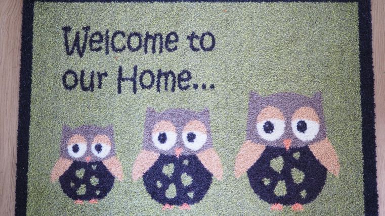 Willkommen Zuhause. Eine Fußmatte mit drei Eulen und einem freundlichen Design.