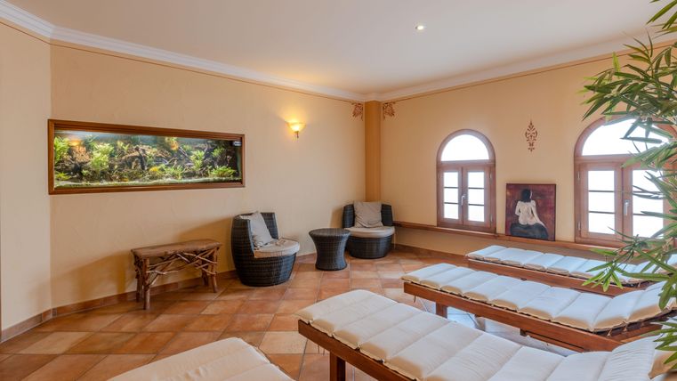 Een ontspannende rustruimte met ligstoelen, uitzicht op een aquarium en warm licht. De ruimte is gezellig en nodigt uit tot ontspanning.