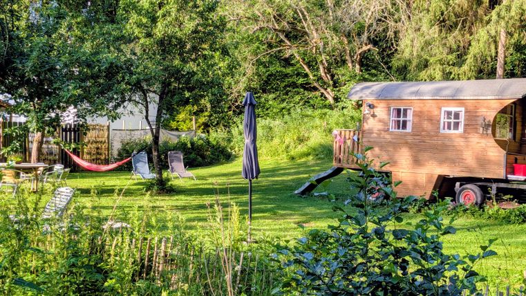 Ein gemütlicher Garten mit einer Holzhütte und einer Hängematte. Die Umgebung ist grün und einladend, ideal zum Entspannen.