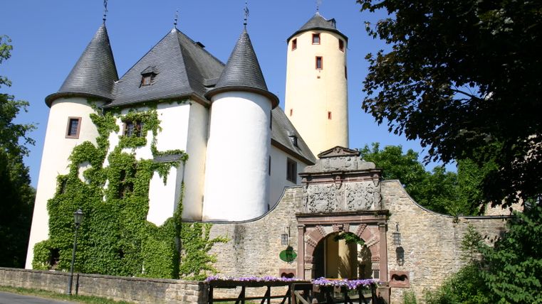 Château de Rittersdorf avec tours et arc de porte, entouré d'arbres.