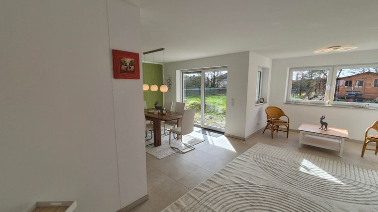 Un salon moderne avec une table à manger et des chaises confortables. De grandes fenêtres offrent une vue sur l'extérieur et beaucoup de lumière naturelle.