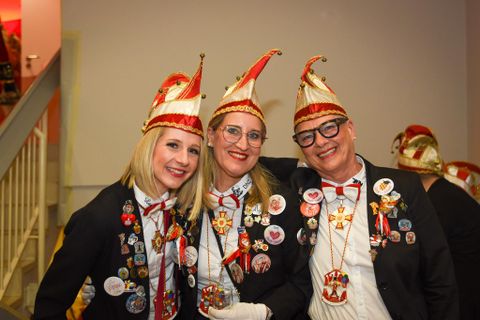 Zwei Frauen in Kostümen haben Spaß. Die eine trägt ein Polizistinnenkostüm, die andere ein formelles Outfit.
