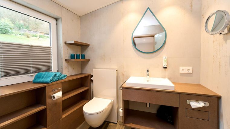 Een moderne badkamer met een eenvoudig ontwerp. Het heeft een wastafel, een toilet en planken van hout.
