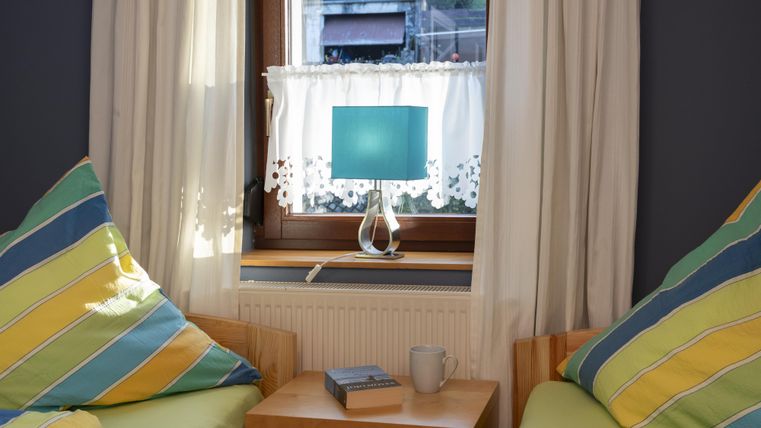 Een gezellige kamer met twee kleurrijke zitzakken en een tafel. Bij het raam staat een lamp met een blauwe lampenkap.
