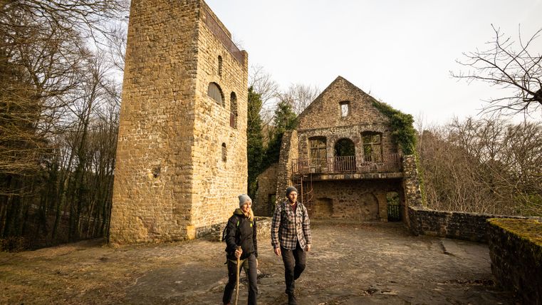 Twee mensen lopen voor de ruïnes van het kasteel van Prüm.