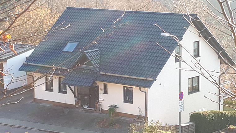 Een modern eengezinswoning met een zwart dak en witte muren. Het bevindt zich aan een rustige straat, omgeven door bomen.