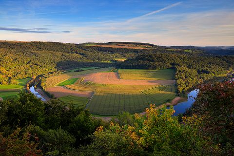 Paysage avec rivière, champs et forêts au coucher du soleil.